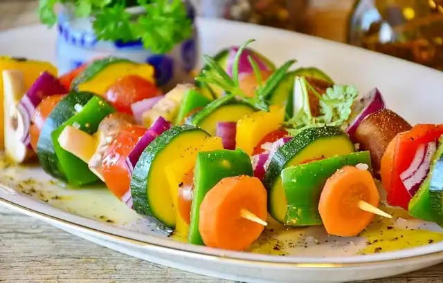Une assiette colorée débordant de délicieuses légumes grillés, accompagnée d'une sauce onctueuse et parsemée de fines herbes fraîches.